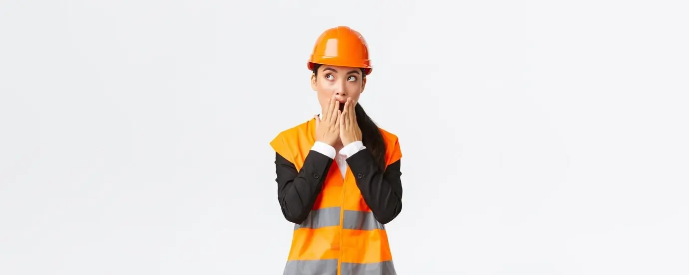 A shocked and concerned Asian female engineer and architect, wearing a safety helmet and a reflective jacket, staring toward the upper left corner and gasping with a worried, amazed expression, standing against a white background.